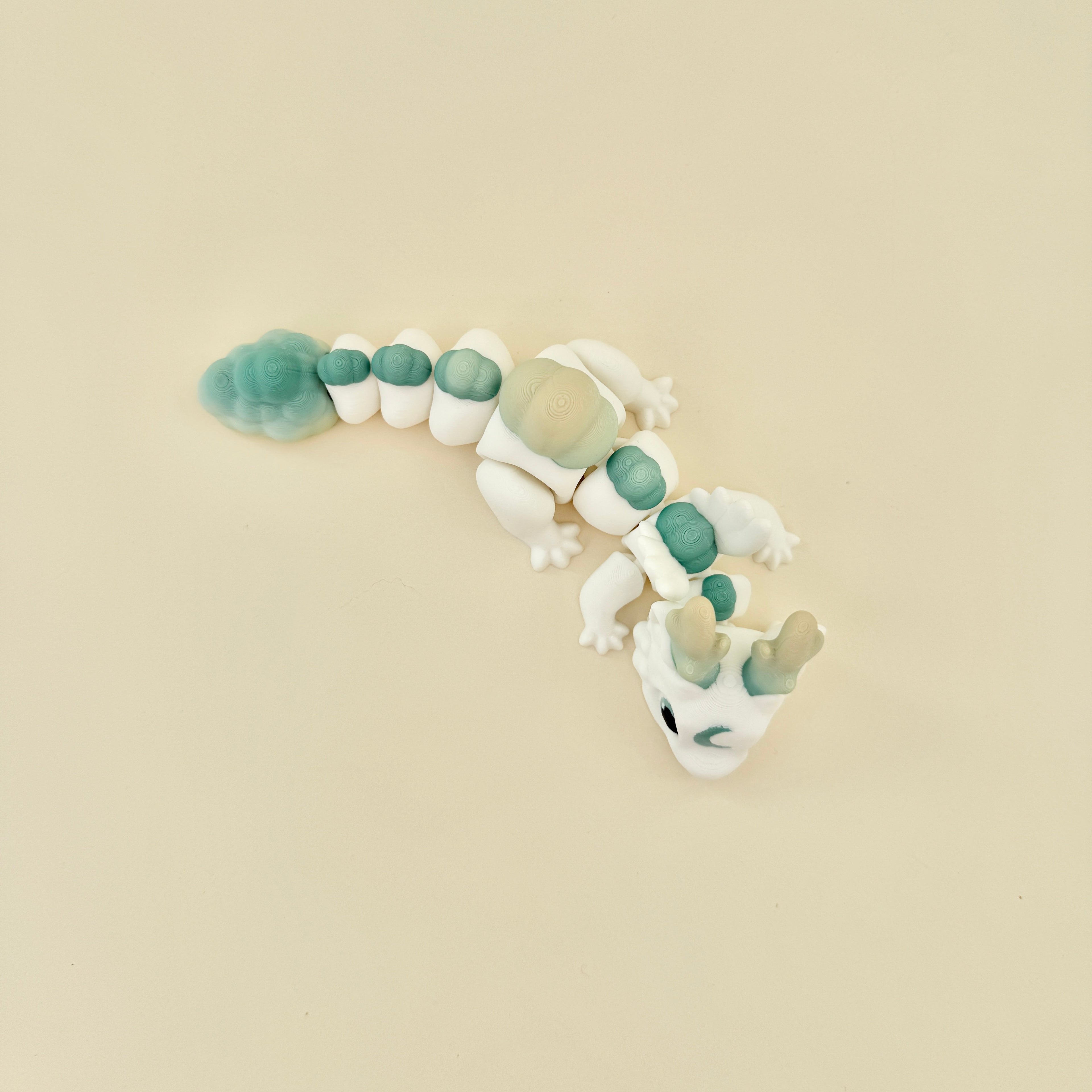 Dragon-style fidget toy with smooth segments and a subtle green and yellow gradient.