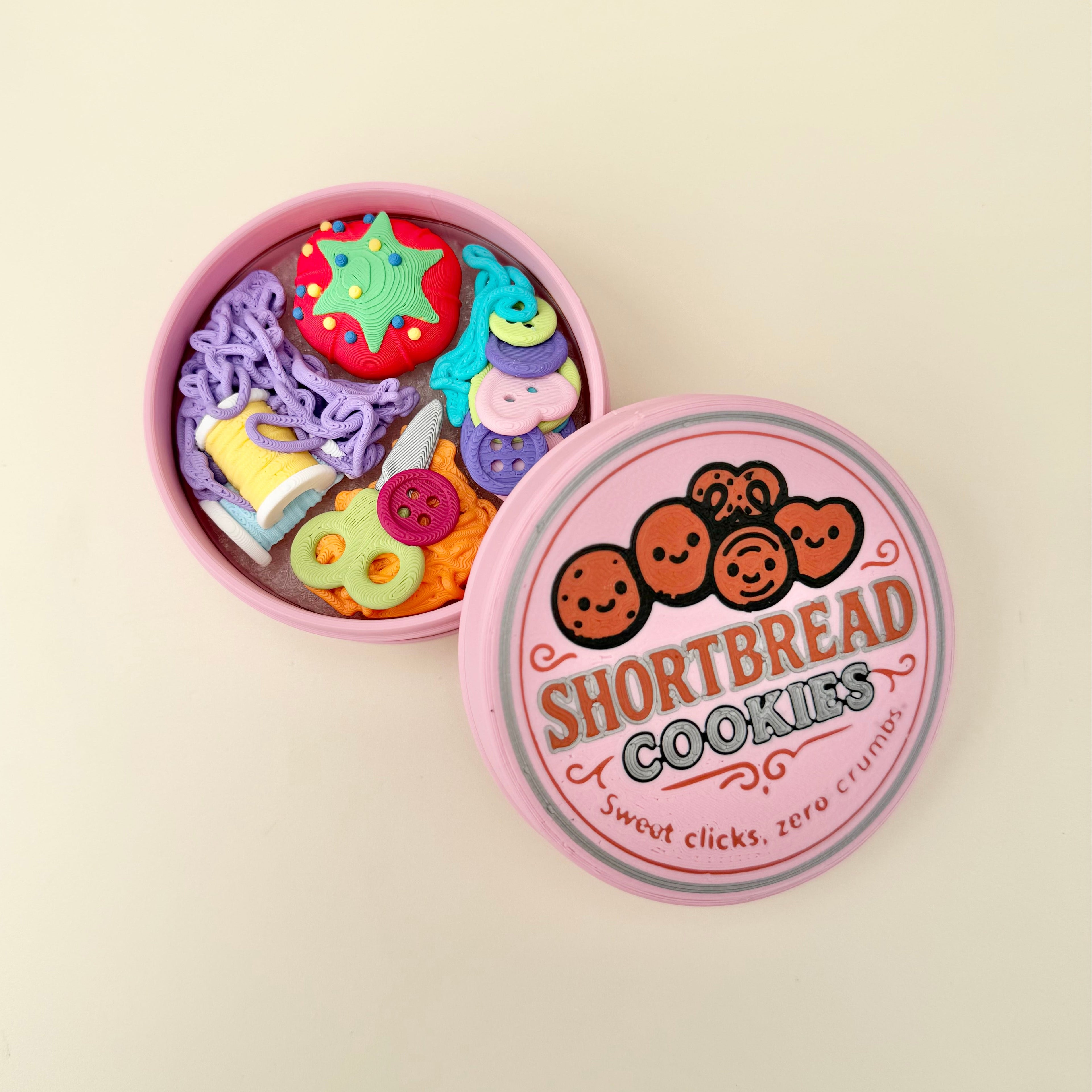Round storage-style fidget tin with detailed craft pieces and multiple clickers for desk fidgeting and focus.
