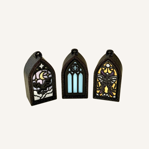 Small stained-glass inspired clicker charm with black sparkle frame and detailed gothic design for tactile everyday use.
