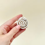 Compact cinnamon roll fidget clicker providing sensory stimulation.