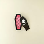 Handheld magnetic snap fidgets with coffin-shaped storage case on neutral background.
