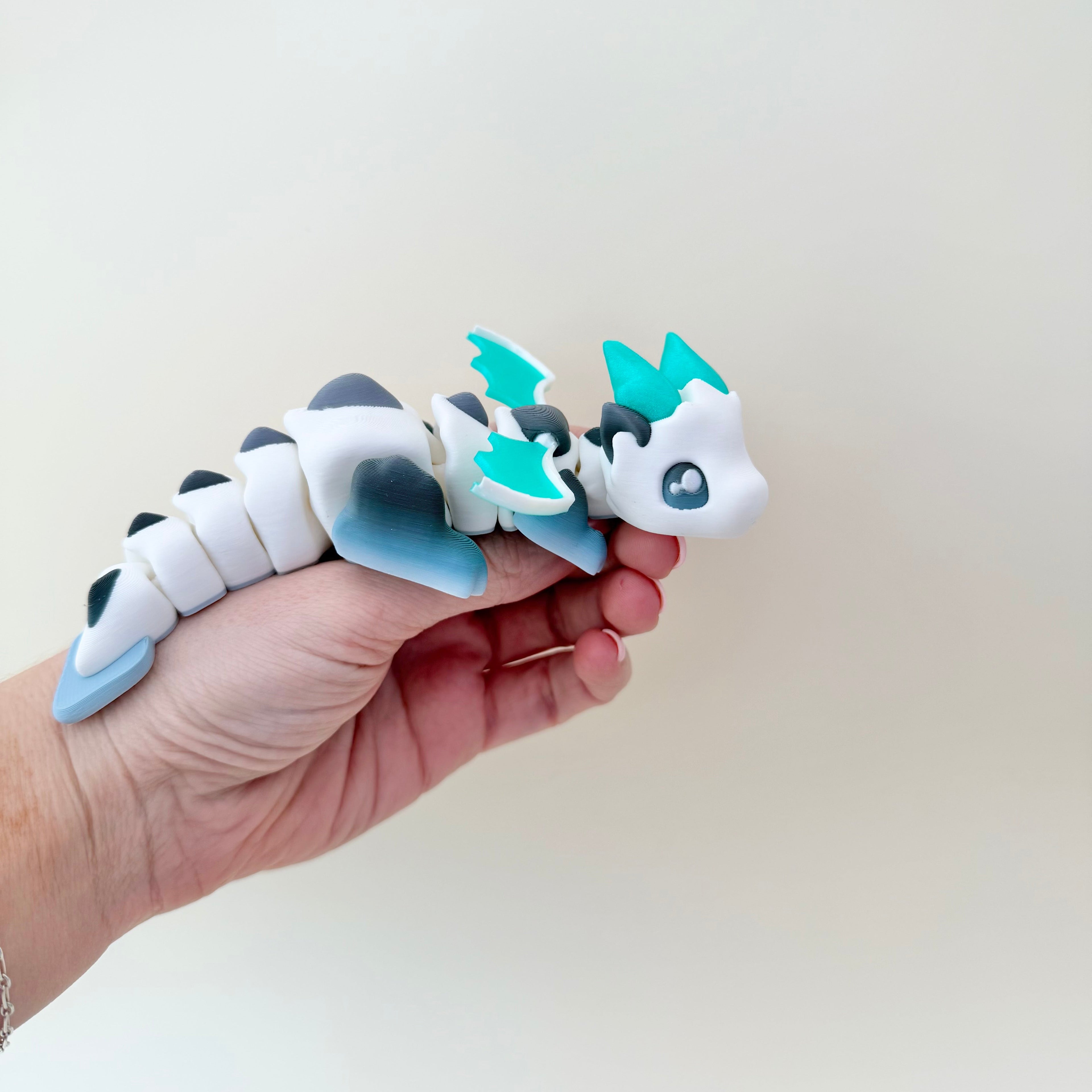 Limited-run articulated dragon for desk display or sensory play, gentle clack movement and ridged texture.
