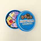 Tin-look fidget container with four internal clickers and raised details for tracing, tapping and stimming.

