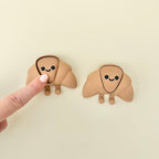 Small croissant-shaped sensory fidget with a cute face and flexible body designed for quiet, gentle tactile use