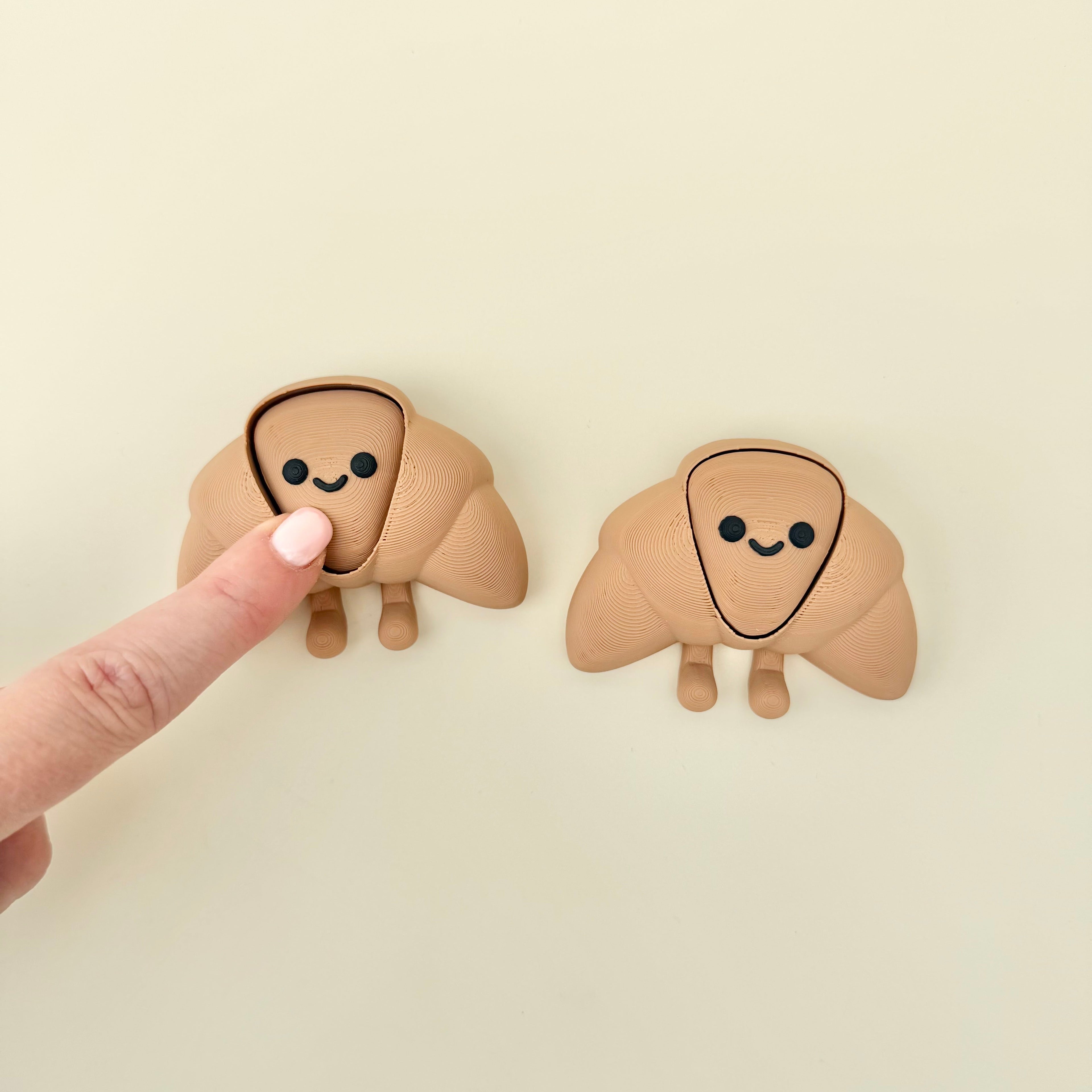 Small croissant-shaped sensory fidget with a cute face and flexible body designed for quiet, gentle tactile use