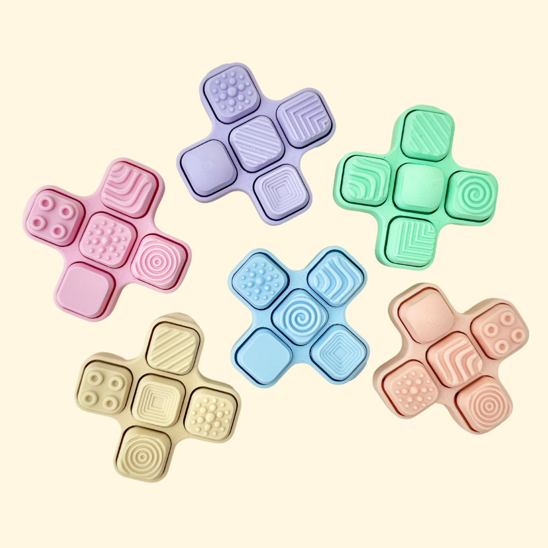 Cross-shaped fidget toy with five clickable panels and a mix of textured and smooth surfaces.