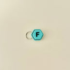 A compact hexagonal fidget toy that clicks when pressed, available with all 26 letters of the alphabet.
