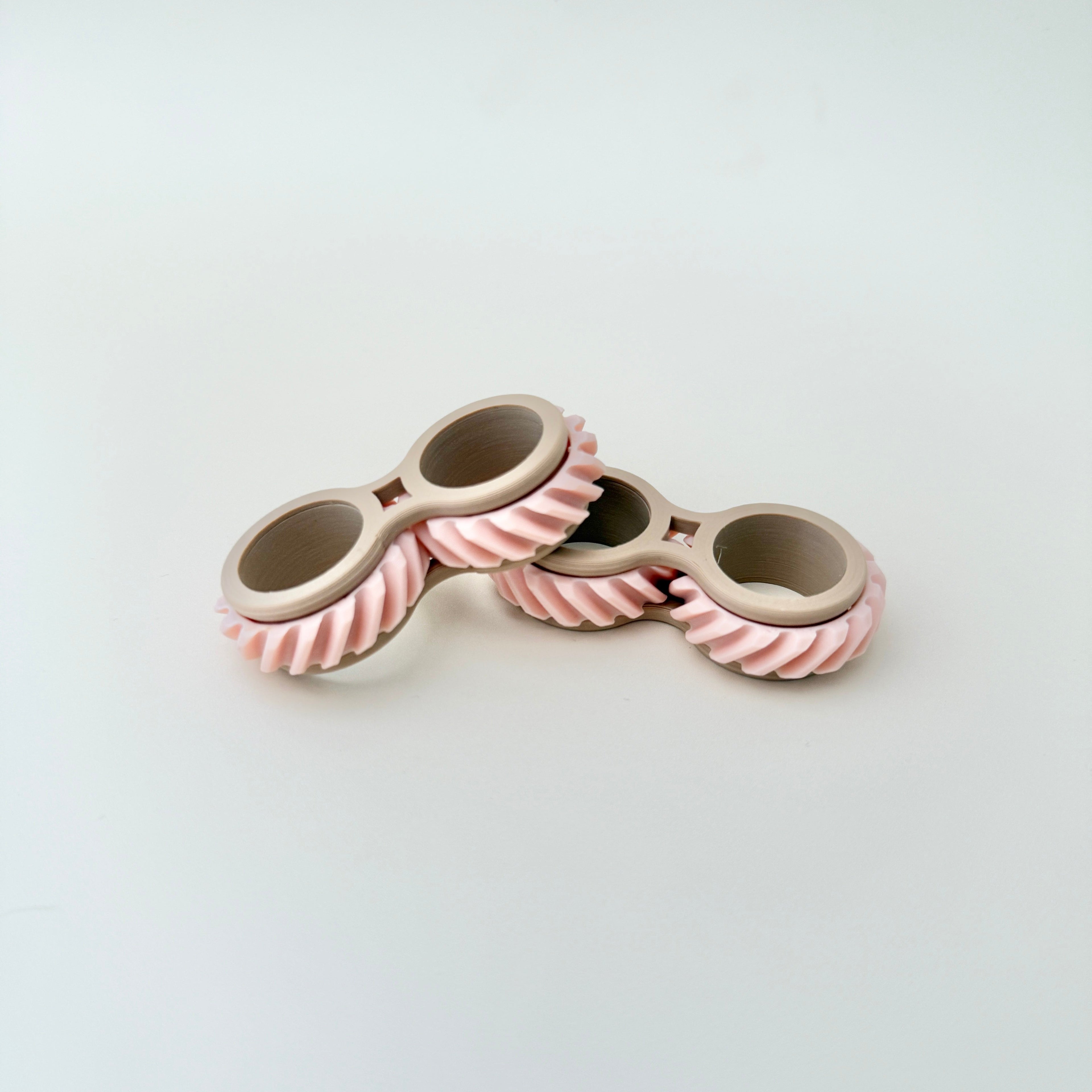 A handheld fidget toy that slides onto two fingers, allowing smooth rolling and twisting for stress relief and focus.