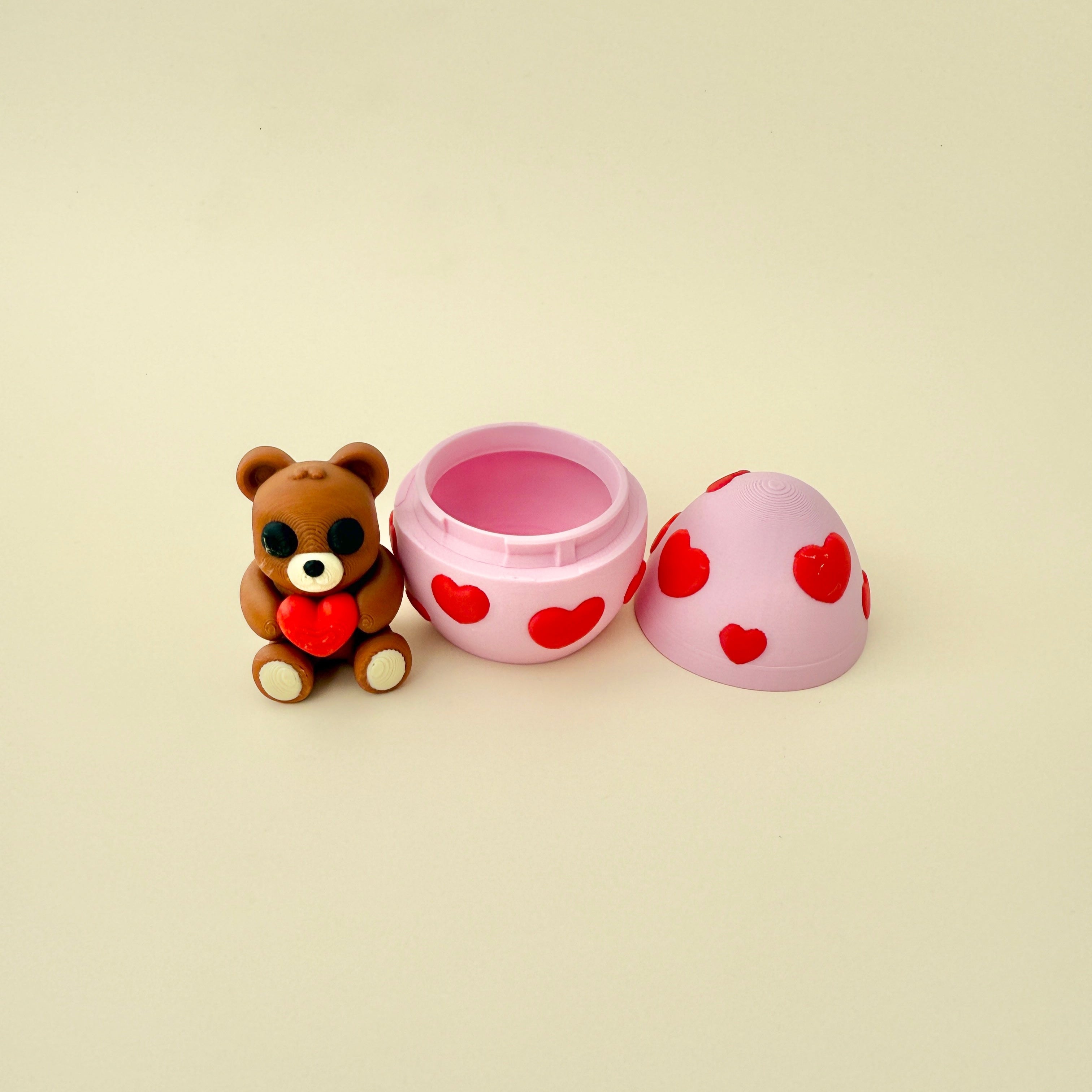 A small beige and brown teddy bear holding a red heart, fully articulated for fidgeting and stress relief.