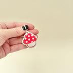 Red-and-white mushroom-shaped sensory toy on loop for bags or keys.
