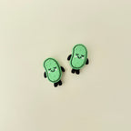 Compact pickle-shaped stim toy with face, limbs, and a firm press-to-click top.