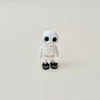 Black cat slippers on a white skeleton with luminous eyes for a playful spooky touch.
