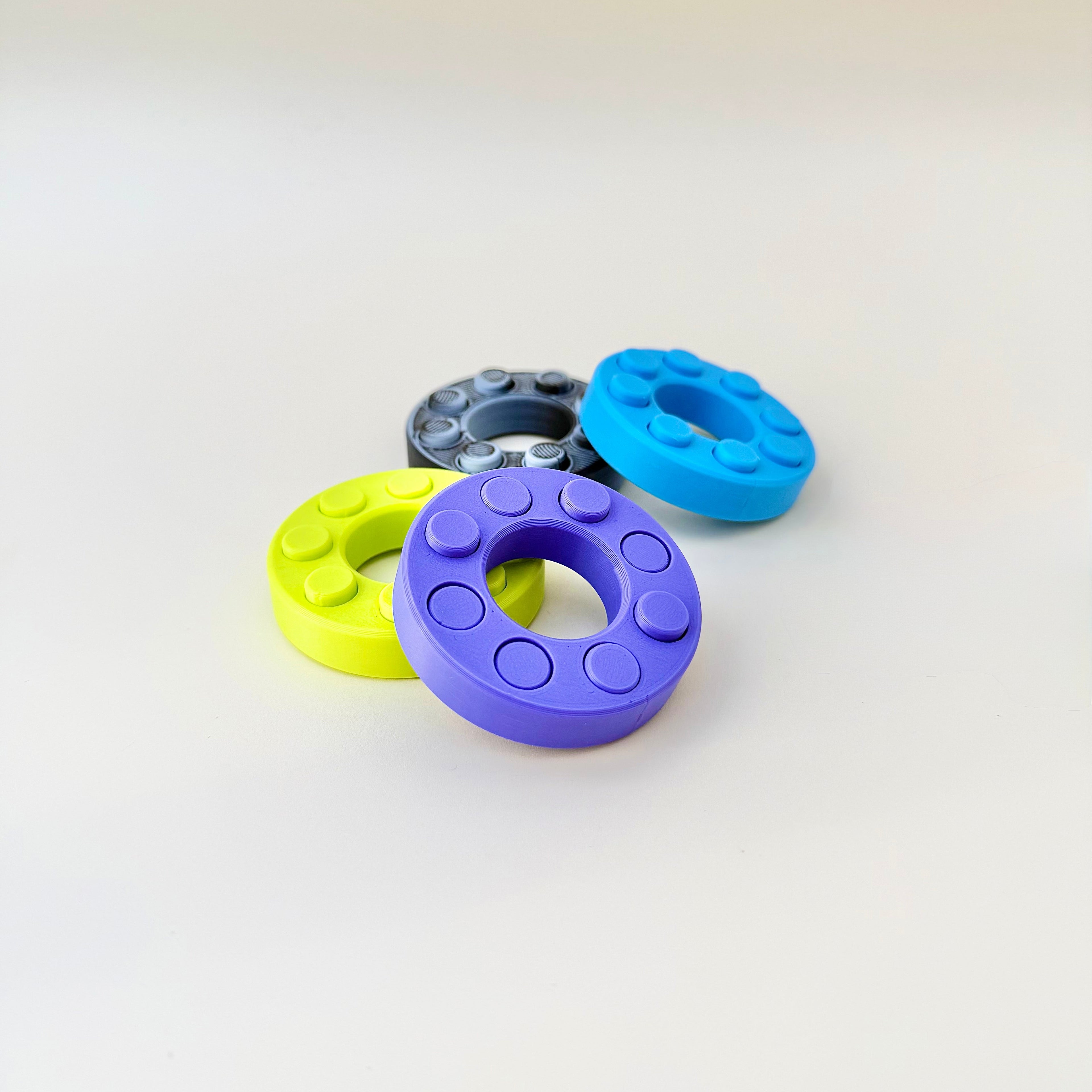 Small circular sensory fidget with eight push buttons for one-handed use
