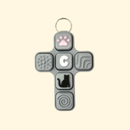 Cross-shaped fidget toy with various textured and shaped buttons on a beige background