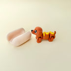 Compact articulated sausage dog with ridged bun; calming, click-free stim toy.
