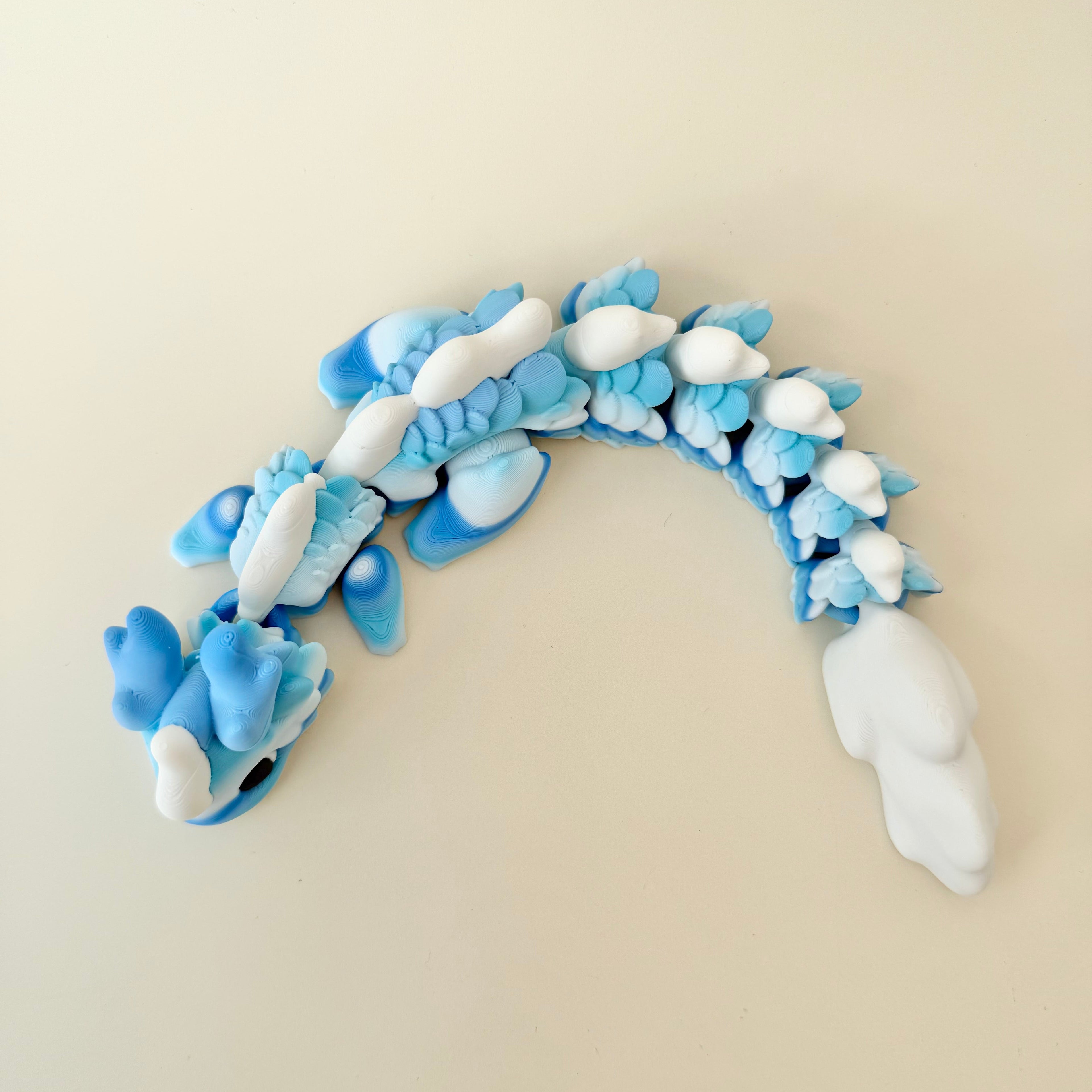 Large articulated dragon fidget, blue-white gradient with tactile scales; quiet feedback; portable and display friendly.
