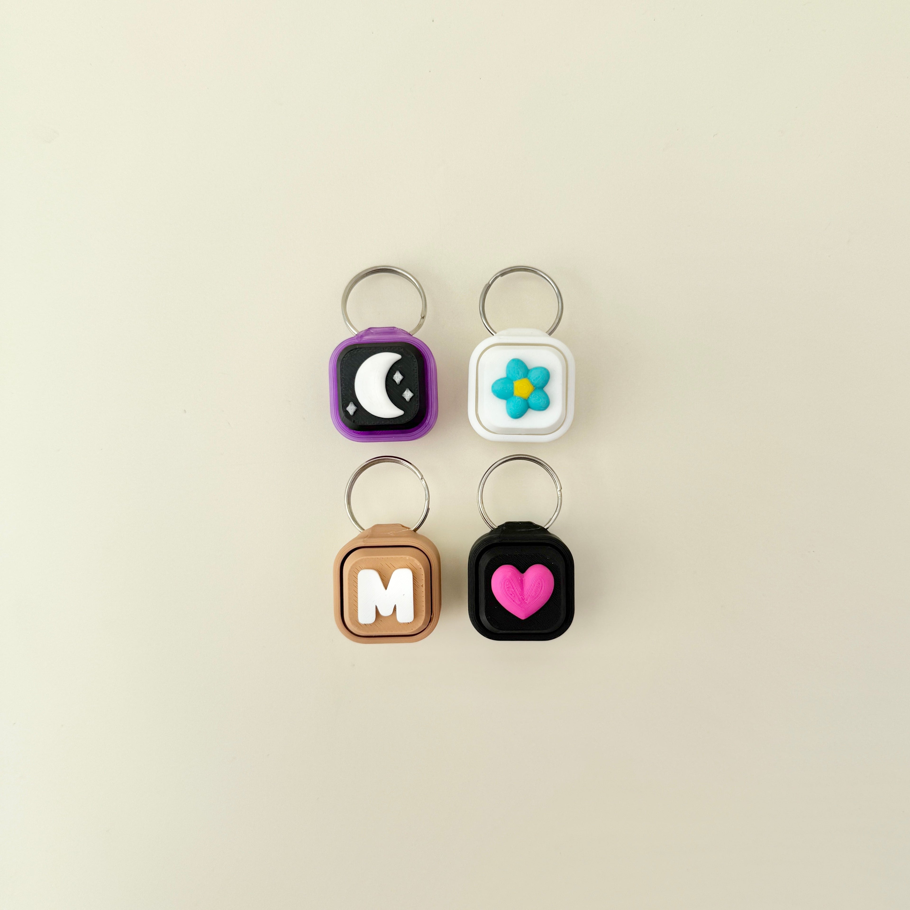 Four keychains with different designs on a beige background