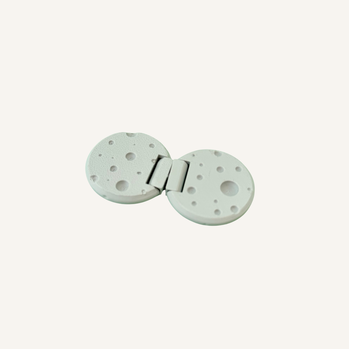 Handheld moon sensory fidget with recessed craters and smooth hinged movement.