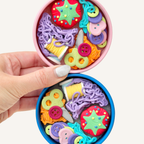 Round tin clicker fidget with removable lid and detailed craft pieces for tracing, tapping and calming hands.
