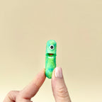 A small, sparkly green pickle toy with interactive features, designed for sensory play.