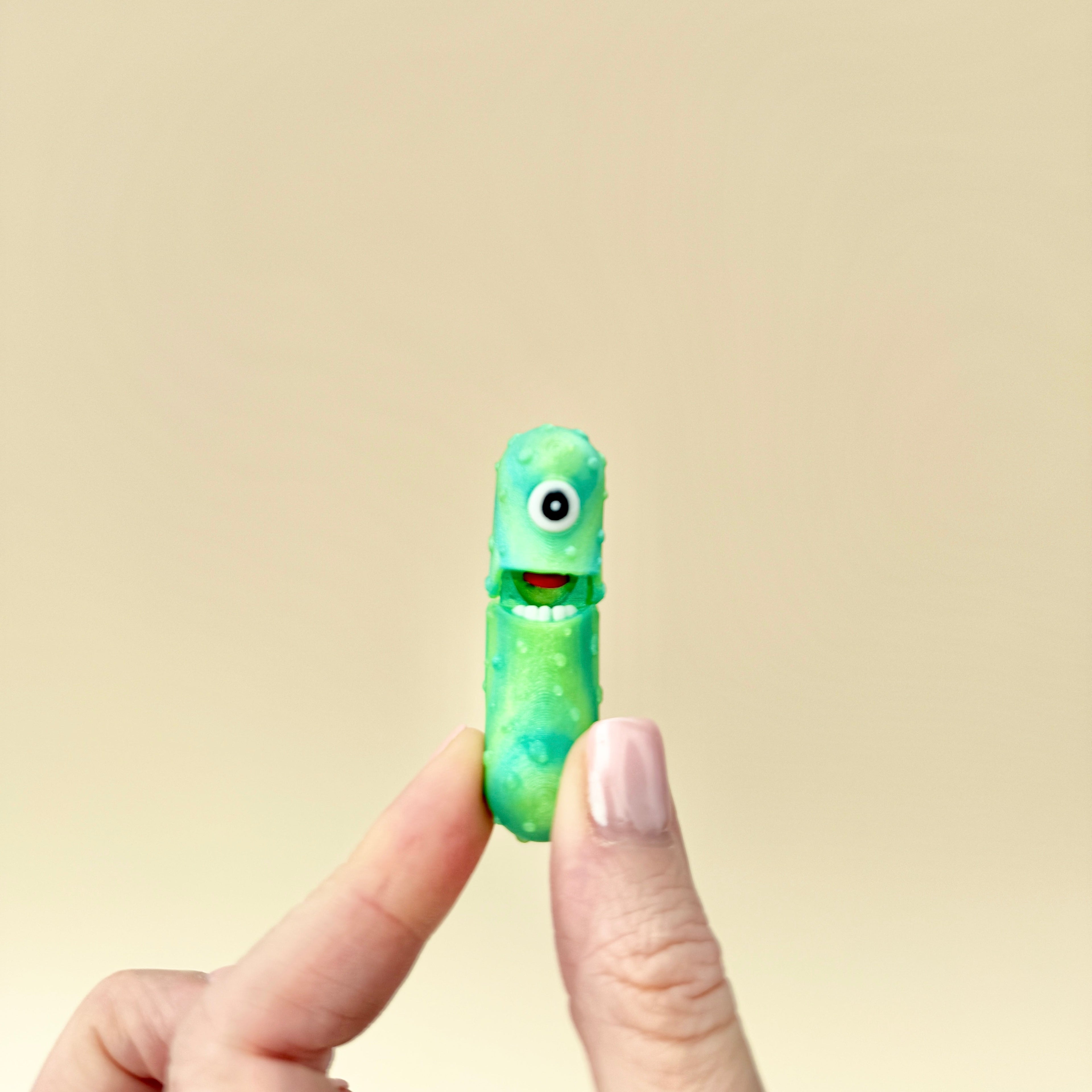 A small, sparkly green pickle toy with interactive features, designed for sensory play.