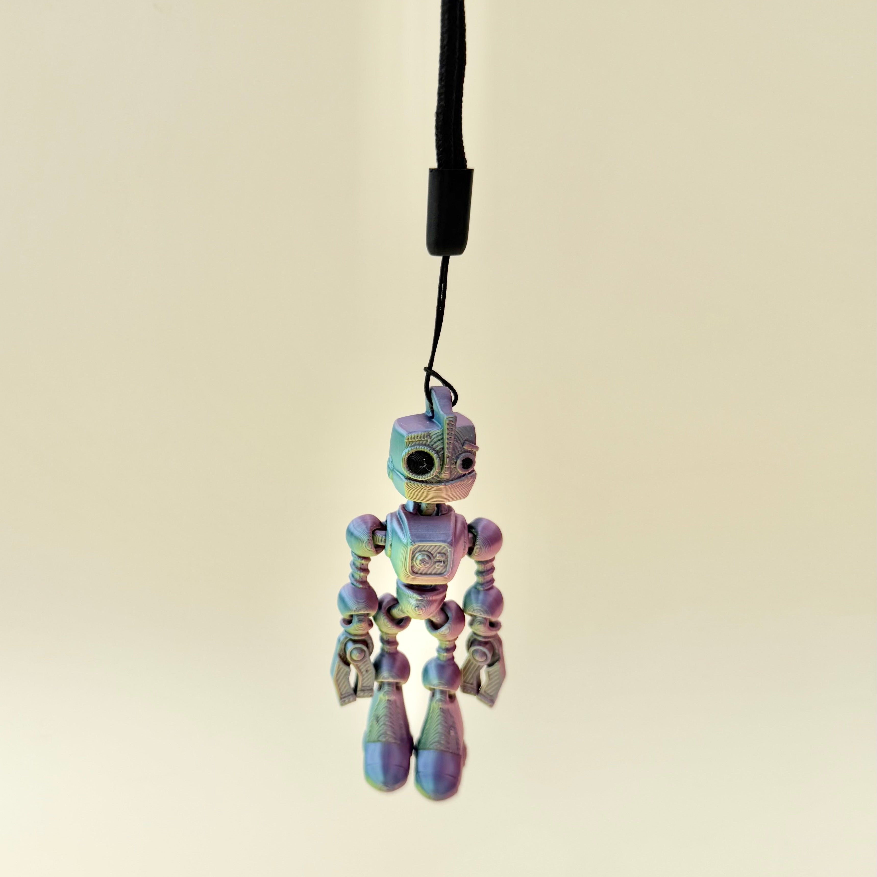 Small robot stim toy with flexible joints, wrist strap attachment and repetitive movement for focus support.
