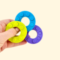 Ring-shaped button fidget with press-through popping action for tactile sensory input
