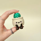 Mini plant pot clicker with poseable legs for sitting on shelves or dashboards, fun tactile click action.
