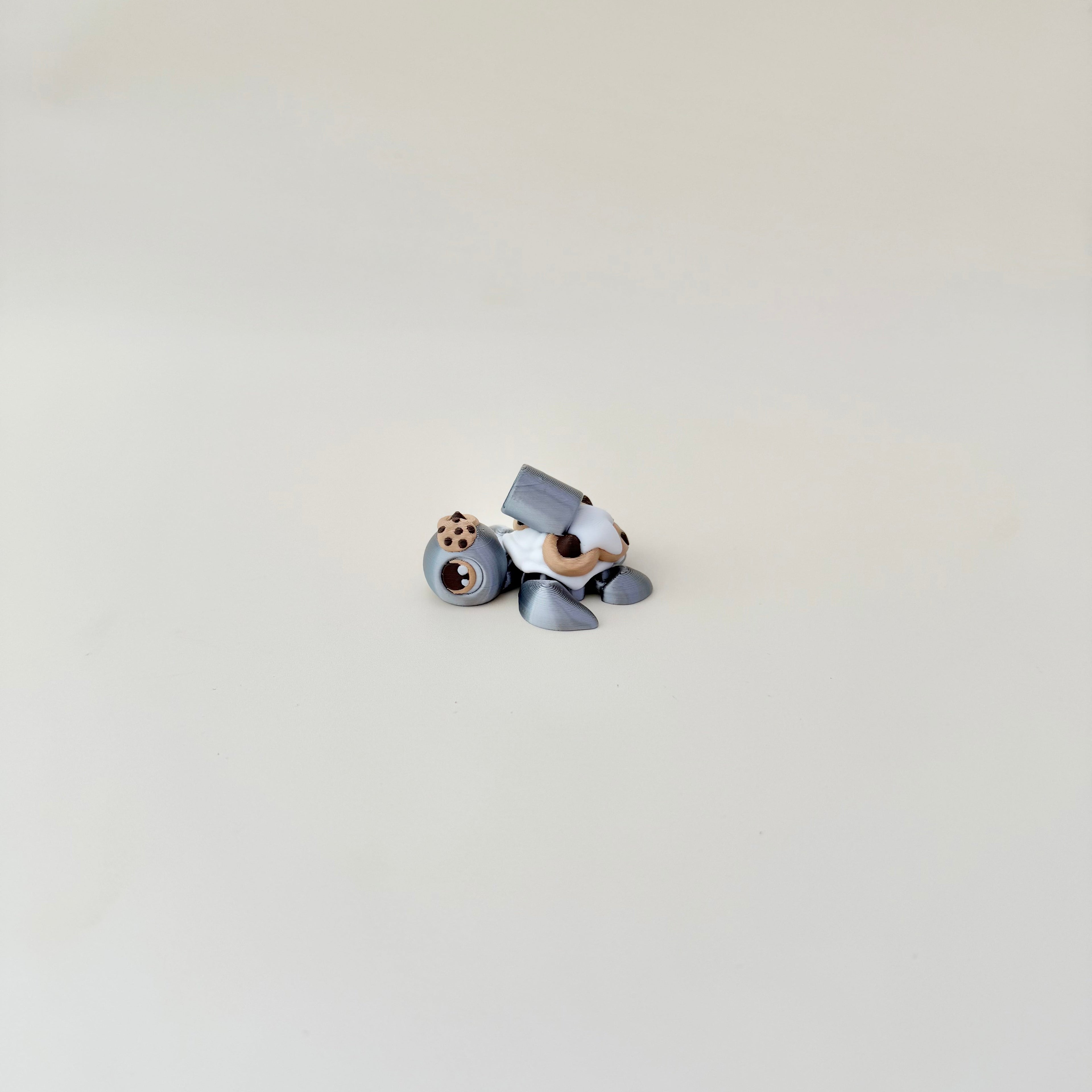 Compact 5 cm articulated turtle in metallic silver with textured cookie back; calming handheld fidget.
