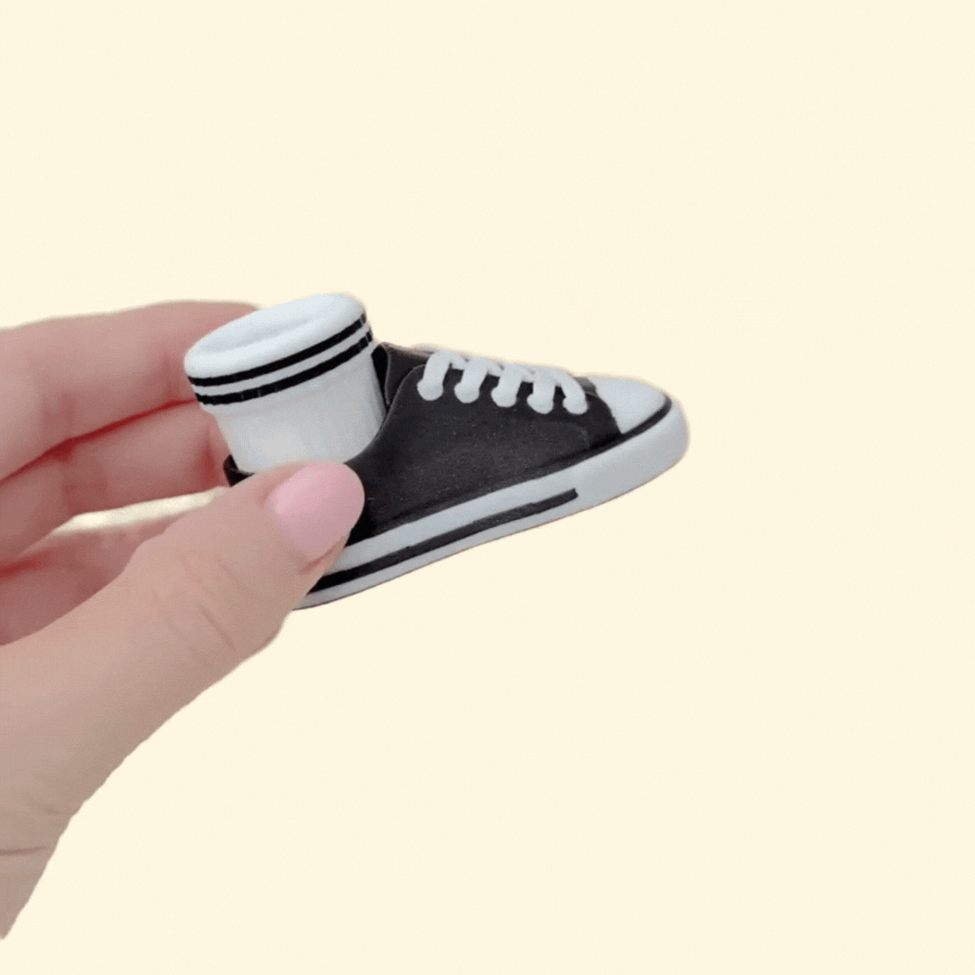 Handheld sneaker-style clicker fidget designed for repetitive pressing and sensory input.

