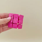 Tactile sensory toy with pop-through buttons that press from both sides.
