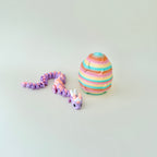 Gradient lilac and peach dragon resting beside a rainbow egg embossed with twinkling stars.