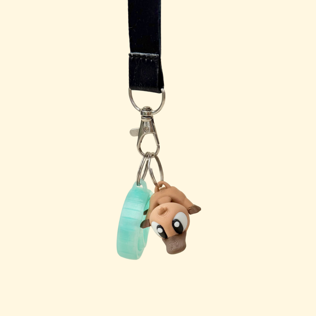 Articulated sensory fidget add-on with smooth and textured details, designed to clip onto lanyards.
