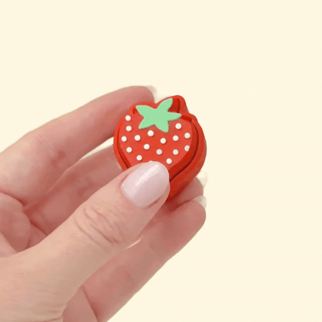 Sensory clicker fidget shaped like a strawberry with green stem and white seed detail.
