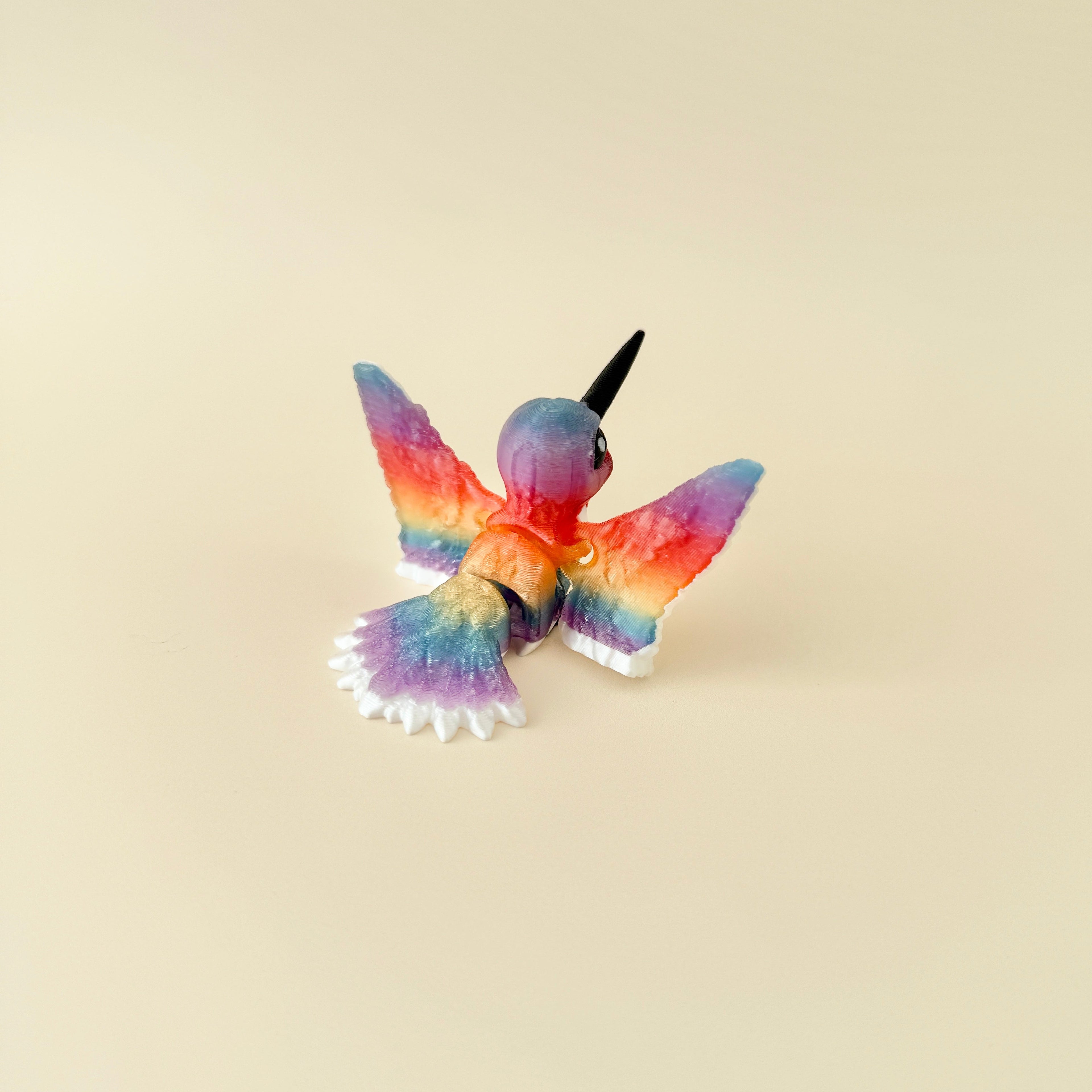 A beautifully detailed hummingbird fidget with white, red, and rainbow accents.