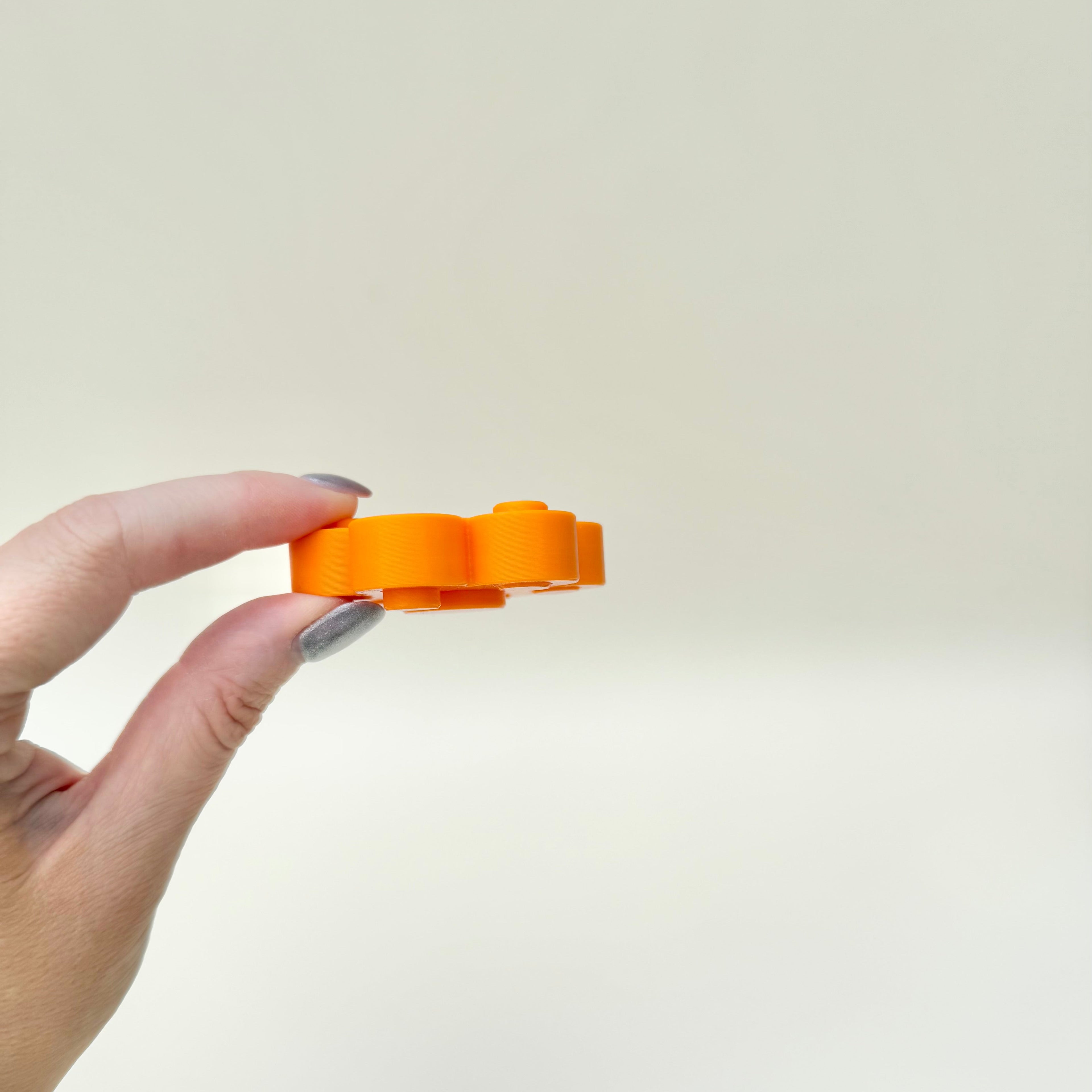 Mini sensory fidget combining spinner motion and pop-back pressing for ADHD and autism friendly stimming.
