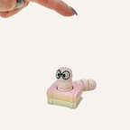 Cute book stack clicker fidget with wiggly tail, satisfying press action, and calming tactile detail.
