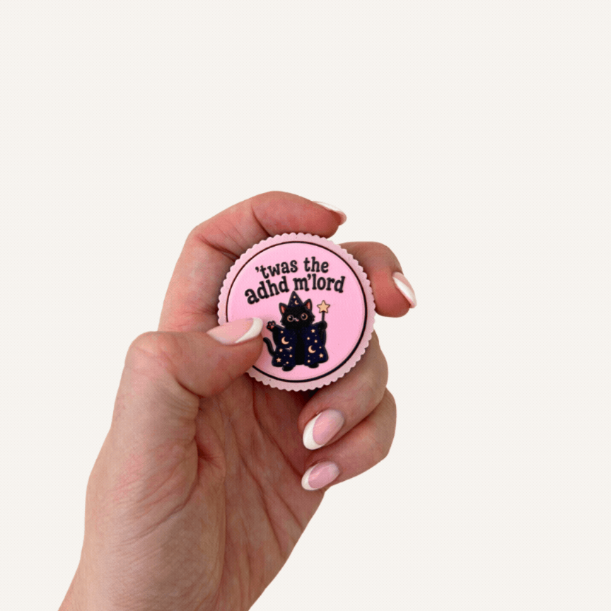 Two pink Twas The ADHD Mlord sensory clickers with wizard cat artwork