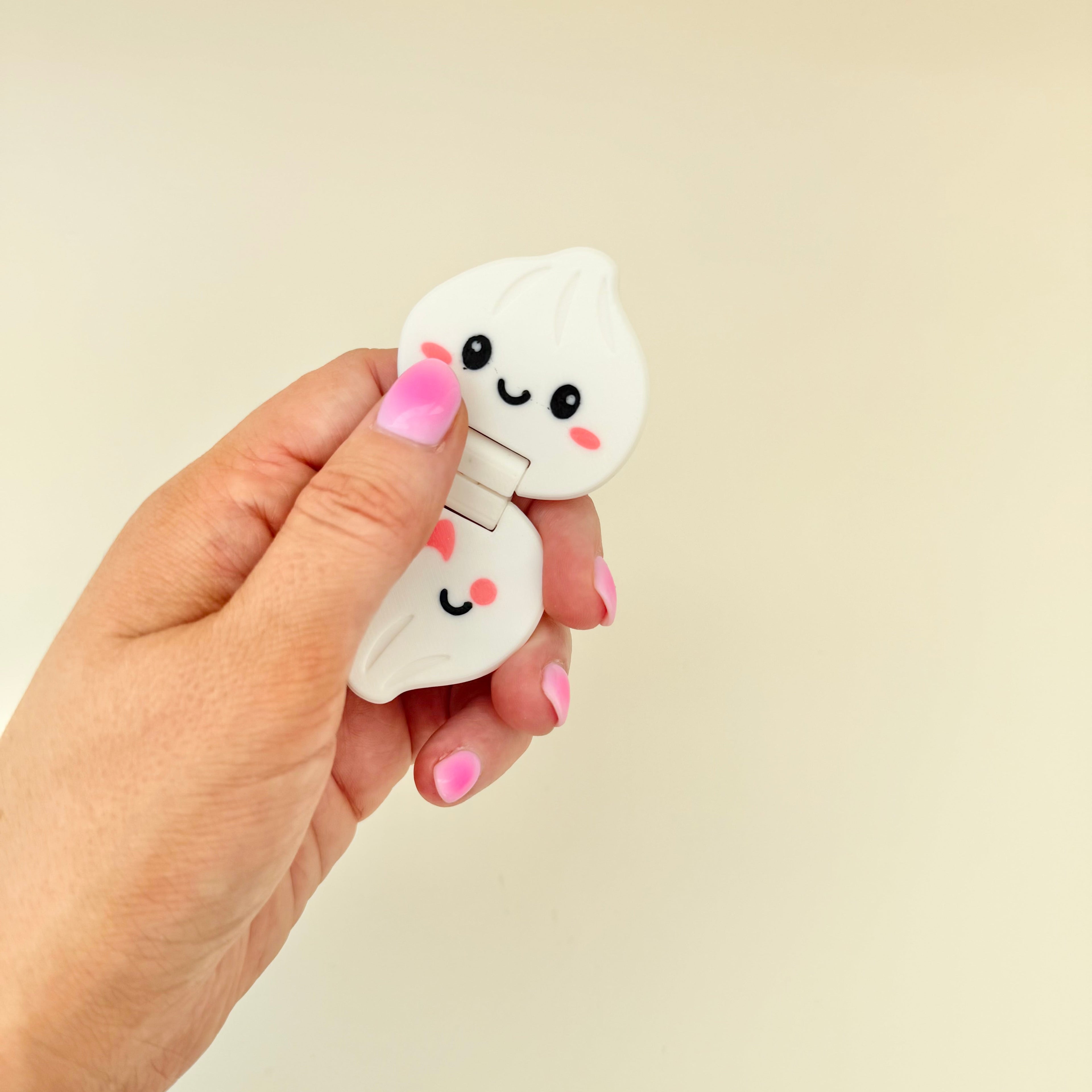 Handheld dumpling fidget with central hinge-style movement for repetitive flipping and tactile feedback.