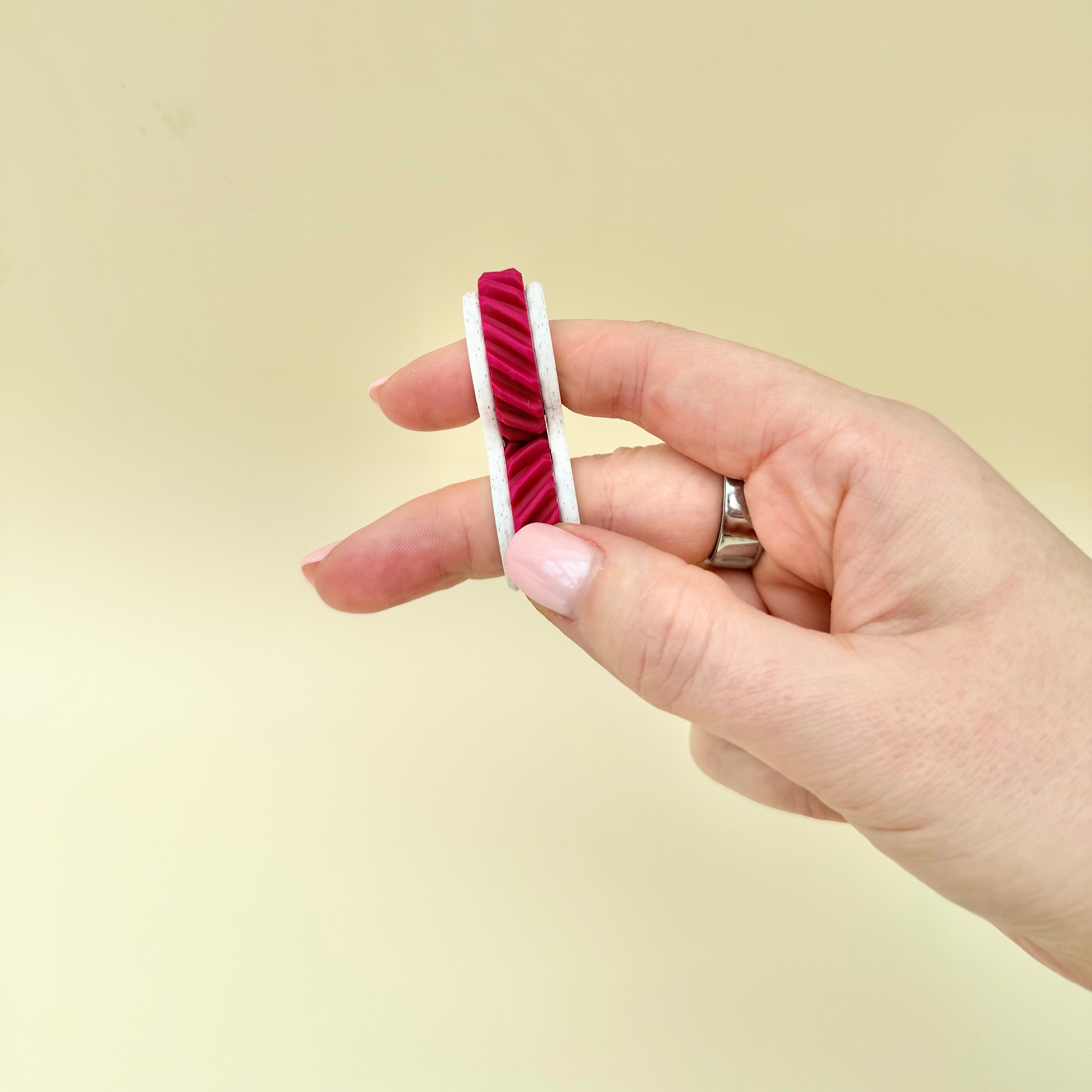 Quiet two-finger sensory fidget with rolling textured wheels for busy hands, grounding and focus support.