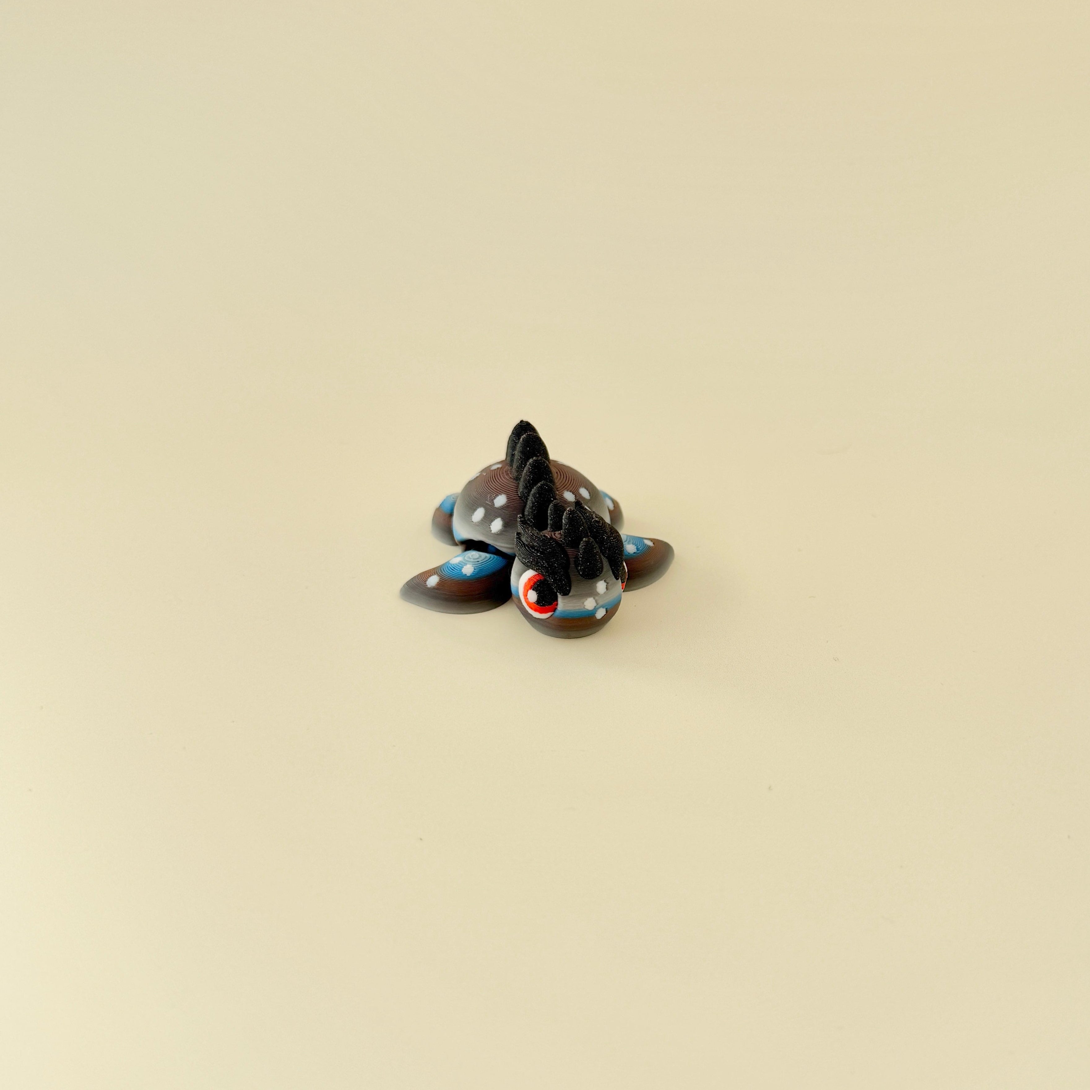 A tactile fidget toy featuring gradient colours in grey, white, brown, and blue with a bold, spiked design.