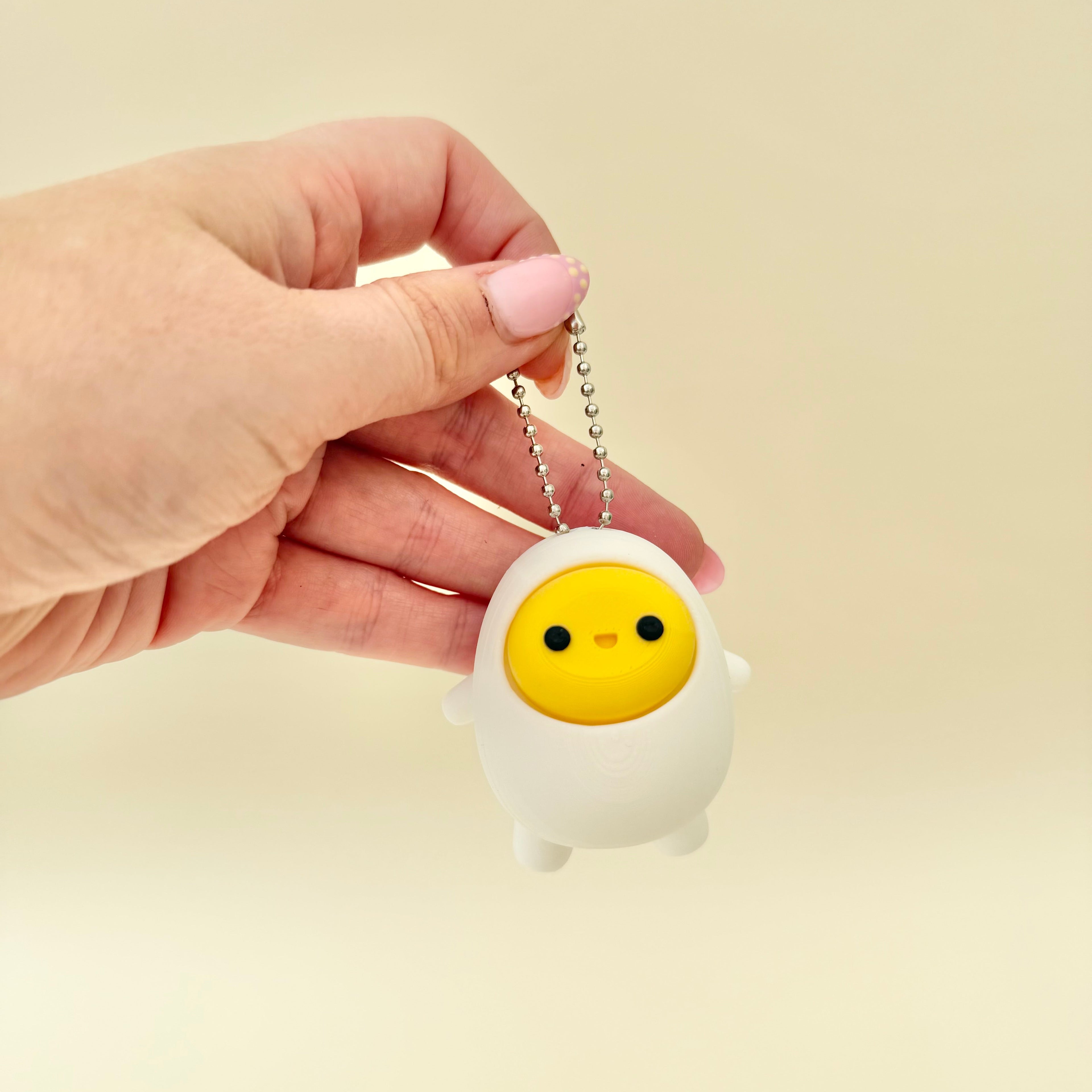 Cute egg-shaped clicker fidget with keyring loop for bags and lanyards, tactile press stim for focus and calming.
