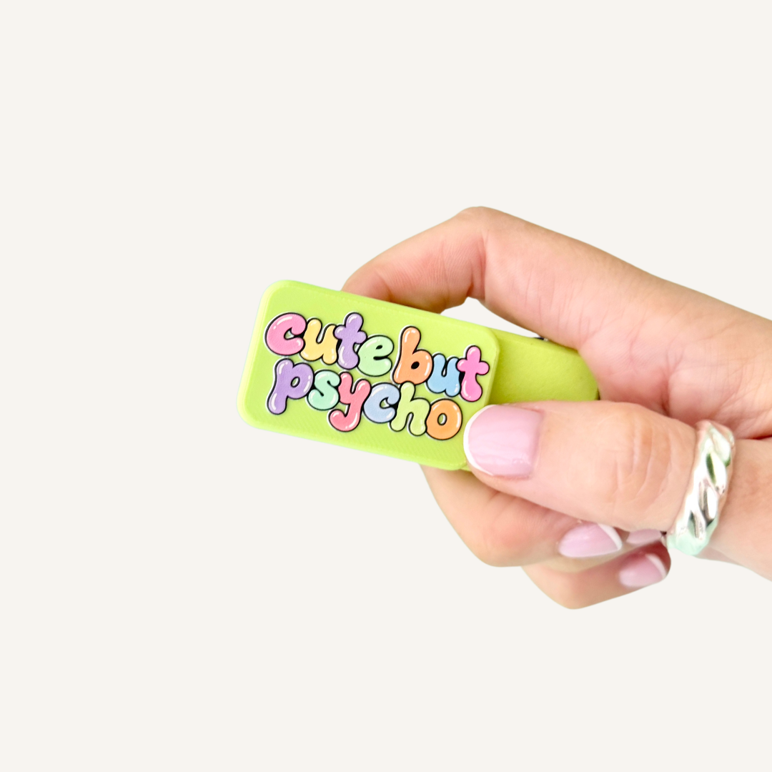 Lime green Cute But Psycho Pocket Magnets held in hand, showing the compact size and raised textured lettering.