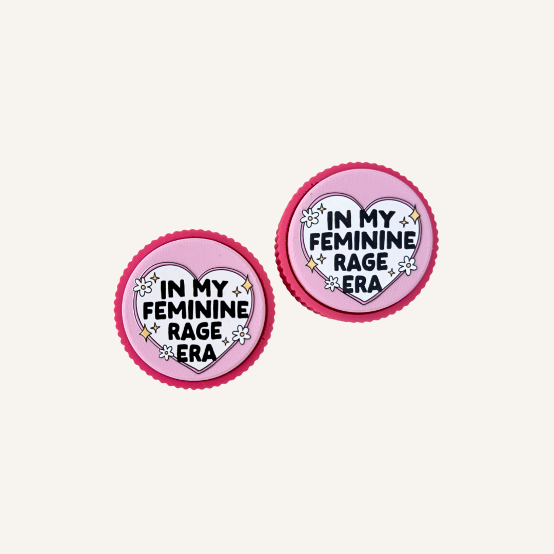 Pink Feminine Rage Clicker with ridged textured edge and raised heart design reading In My Feminine Rage Era.