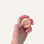 Pink and lime Meet Me at the Bookstore sensory clicker with raised lettering and tactile ridged edge.