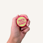 Hot pink and lime green round sensory clicker with raised bookish lettering and textured outer edge.