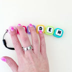 Custom linked letter clicker fidget with pressable buttons, ribbed texture and flexible movement for sensory support.